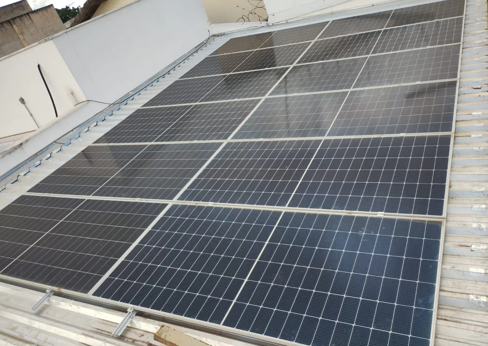 Arranjo com dezenas de painéis solares fixados sobre telha metálica