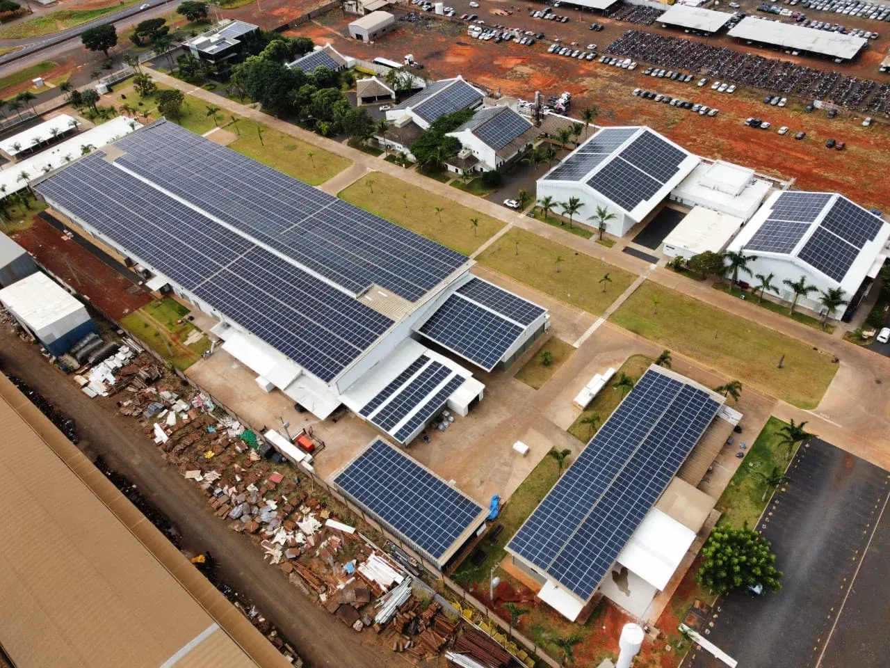 Vista aérea de complexo industrial com usina solar ocupando os telhados de vários galpões